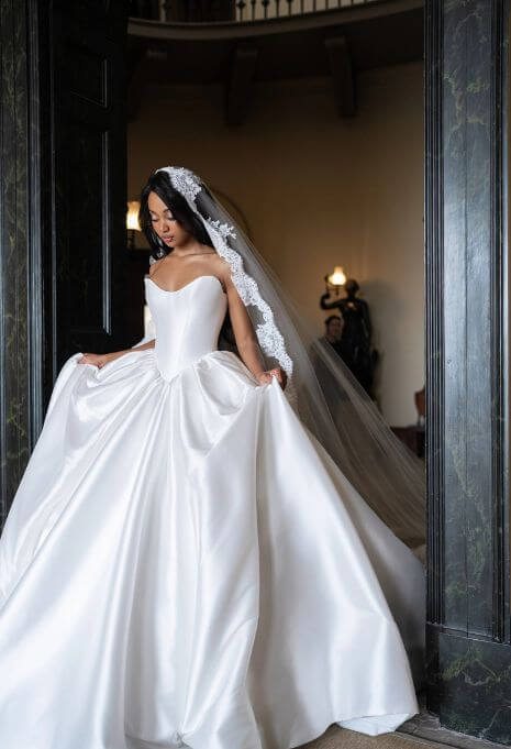 Model wearing Blanche Bridal Manon holding dress with veil